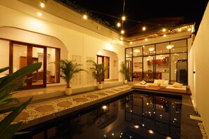 Un intérieur d’hôtel moderne avec une piscine, des plantes en pot et un espace repas.