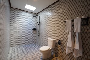 Une salle de bain avec des toilettes, une douche et des murs carrelés.