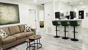 Een moderne woonkamer met een bank, een salontafel en een keukenhoek met een bar.