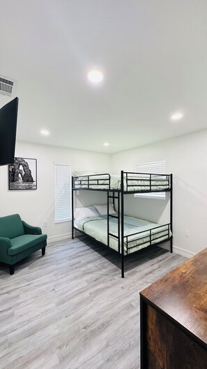 A bunk bed room with a green sofa, a wooden table, and a picture on the wall. - Rustic Cozy Duplex Unit Near IMG & Beaches (Bradenton)