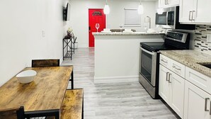 Een moderne keuken met witte kasten, een centraal eiland en een eethoek met een houten tafel en stoelen.