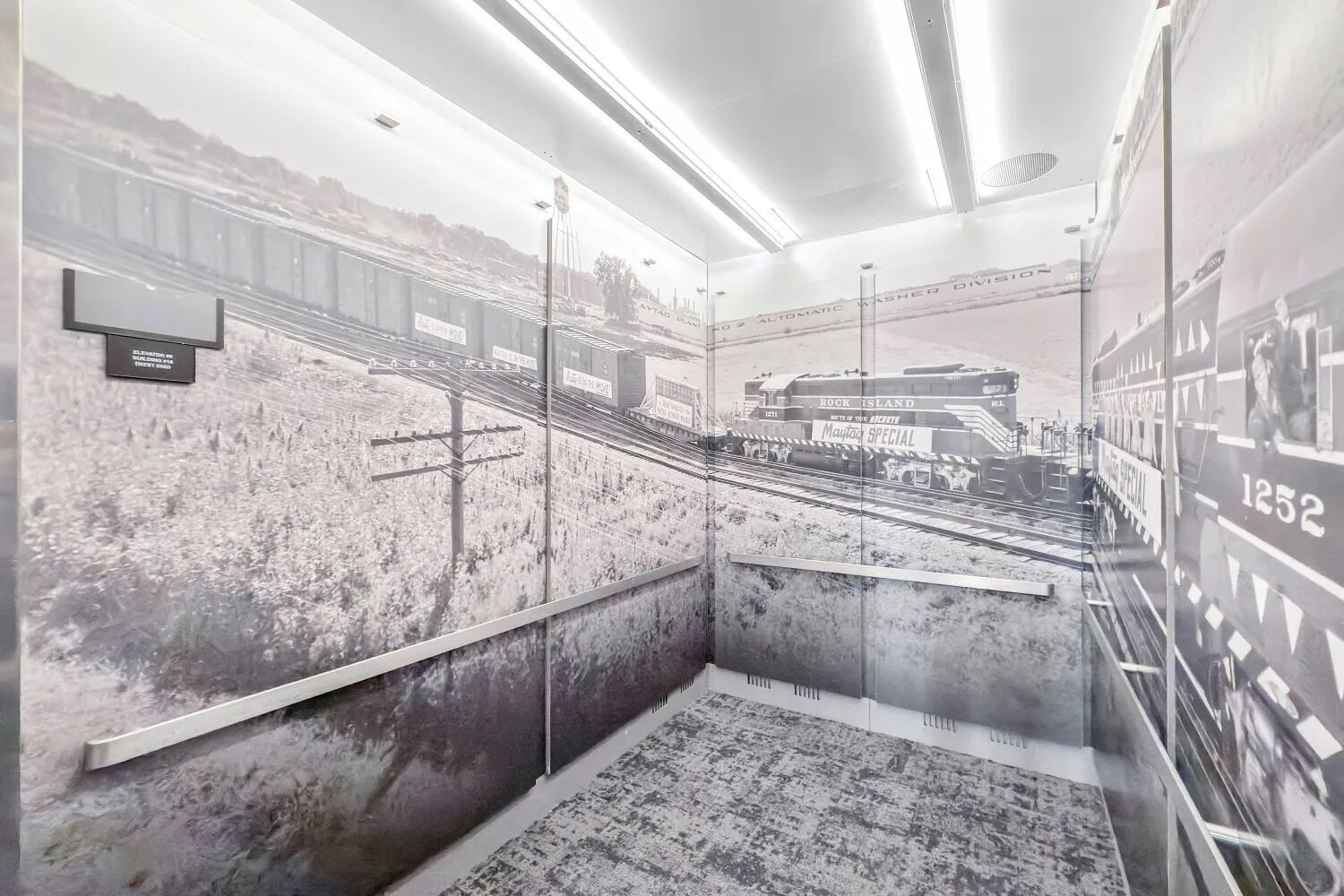 A room with a mural of a train station, a bed, and a nightstand.