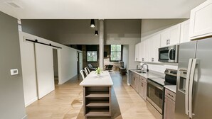 Uma cozinha moderna com uma ilha central, eletrodomésticos de aço inoxidável e vista para uma área de jantar.