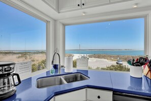 A kitchen with a view of the beach, a coffee maker, and a sink. - Point of View- Beachfront, dog-friendly 4-BR townhome with unbeatable views (North Topsail Beach)