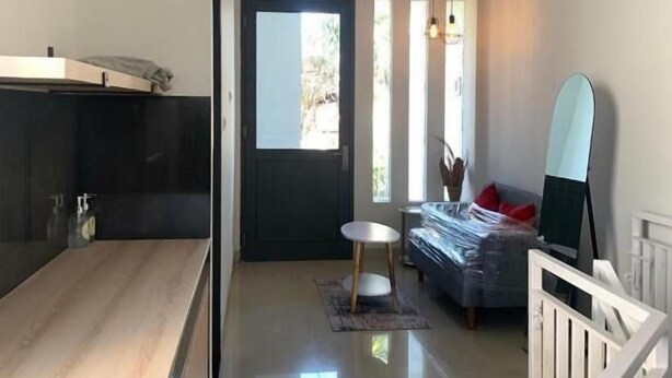A modern room with a kitchen area, a dining table, and a sofa. - Sanur House Lavender (Denpasar)