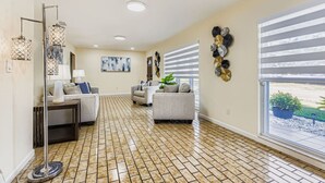 A spacious living room with a tiled floor, two sofas, a coffee table, and a floor lamp. - New Sunrise Sanctuary, 4BR home w/ pool & jacuzzi (Tampa)