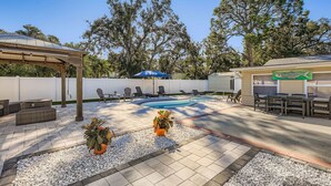 A backyard with a swimming pool, outdoor seating, and potted plants. - New Sunrise Sanctuary, 4BR home w/ pool & jacuzzi (Tampa)