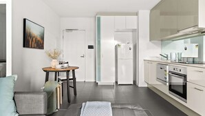 Eine moderne Küche mit weißen Schränken, einem eingebauten Backofen und einem Essbereich mit Tisch und Stühlen.