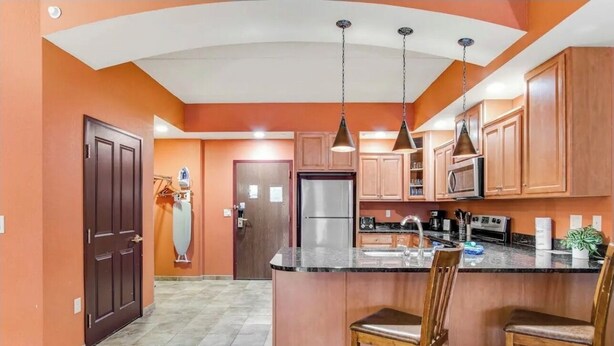 A kitchen with wooden cabinets, a central island with bar stools, and pendant lighting. - Karmak 2 bedroom condo on the first floor. (Wisconsin Dells)