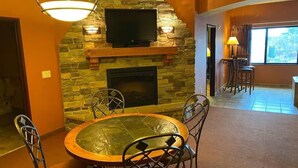 A dining area with a stone fireplace, a round table, and metal chairs. - Karmak 2 bedroom condo on the first floor. (Wisconsin Dells)