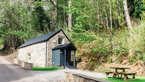 A stone building with a small porch, a picnic table, and a gravel path leading to it. - Wayside Bothy by Interhome (Drumnadrochit)