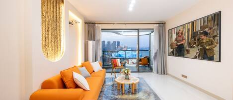 A modern living room with a sofa, a coffee table, and a large window with a city view.