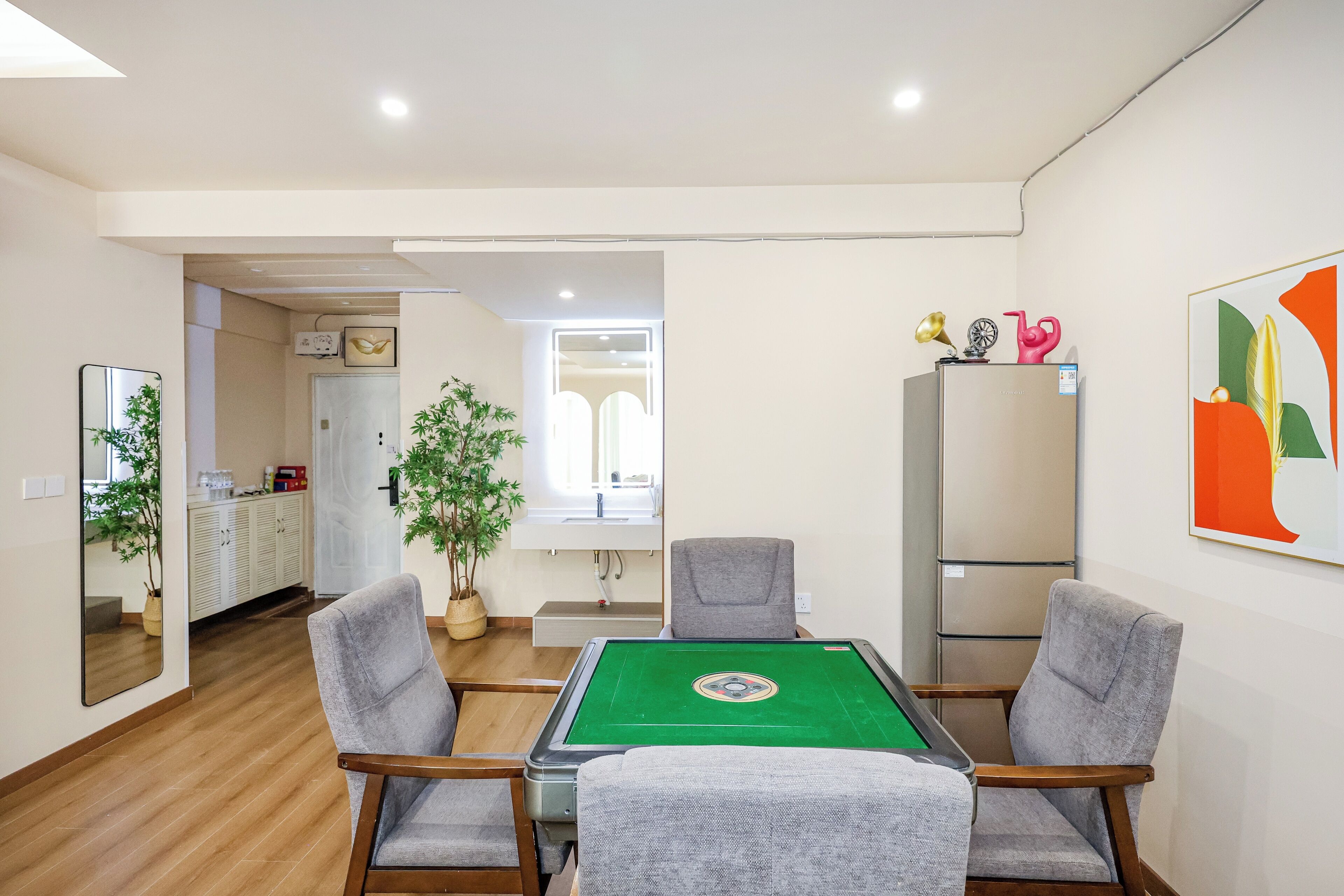 Ein Zimmer mit Billardtisch, vier Stühlen, einem Kühlschrank und einer Topfpflanze.