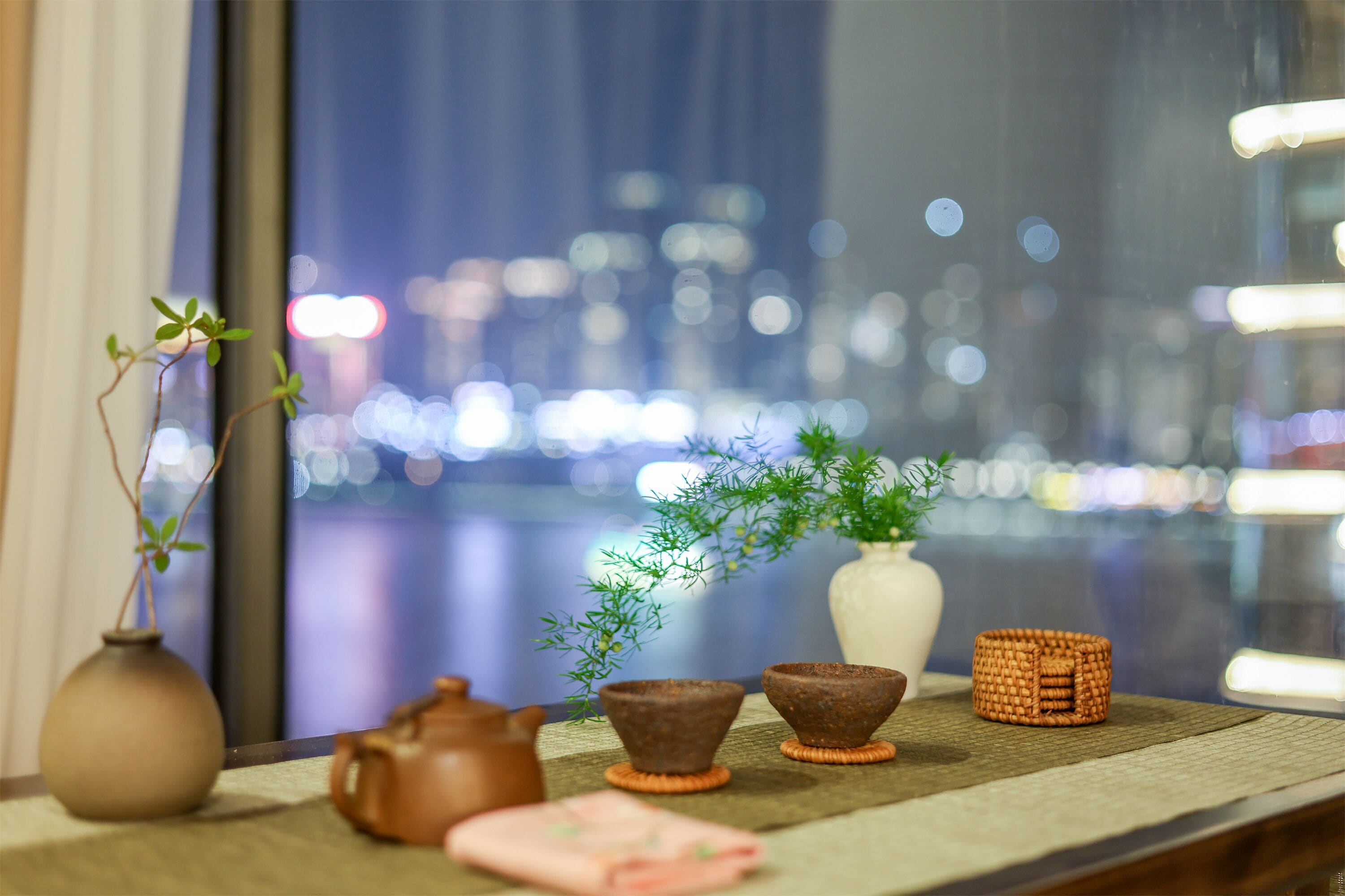 A table with a vase, a teapot, a bowl, a small plant, and a woven basket.