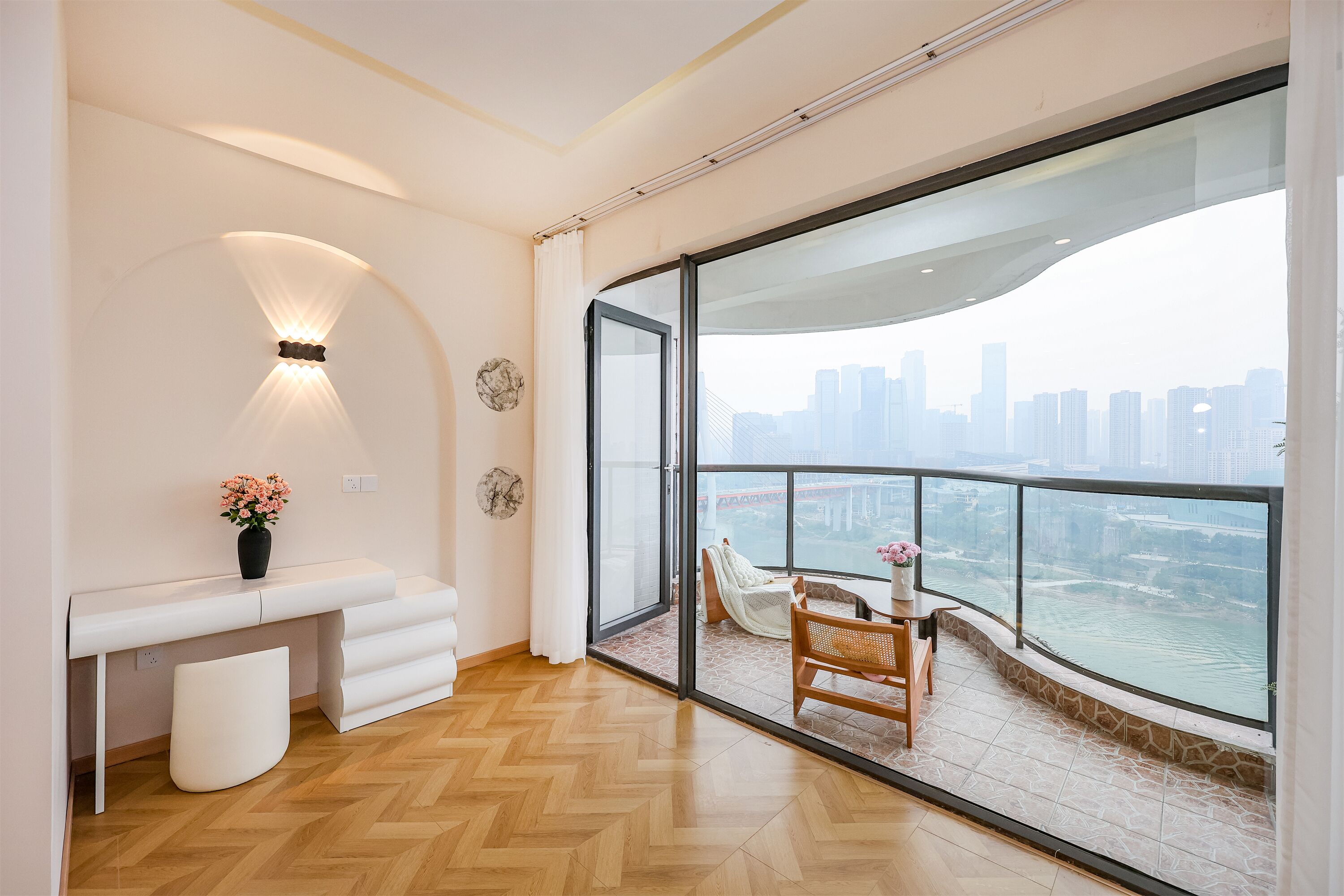 A modern room with a large window, a white desk, a chair, and a view of a cityscape and river.