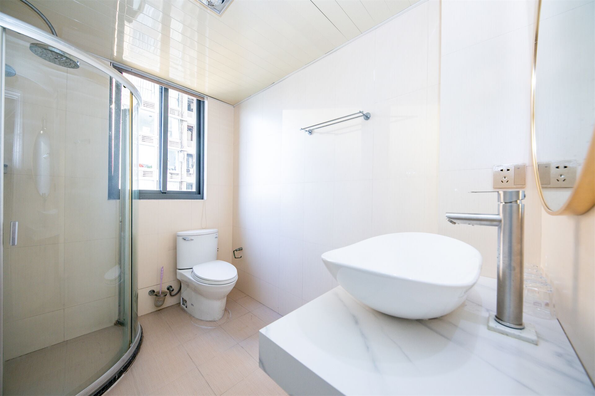 Une salle de bain moderne dotée d’une douche à parois de verre, de toilettes et d’un grand lavabo avec un plan de travail en marbre.