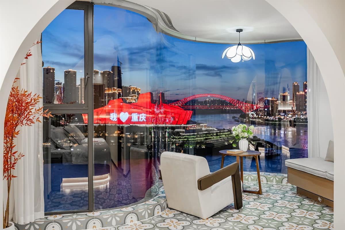 A modern room with a curved glass wall, a sofa, a small table, and a decorative plant.