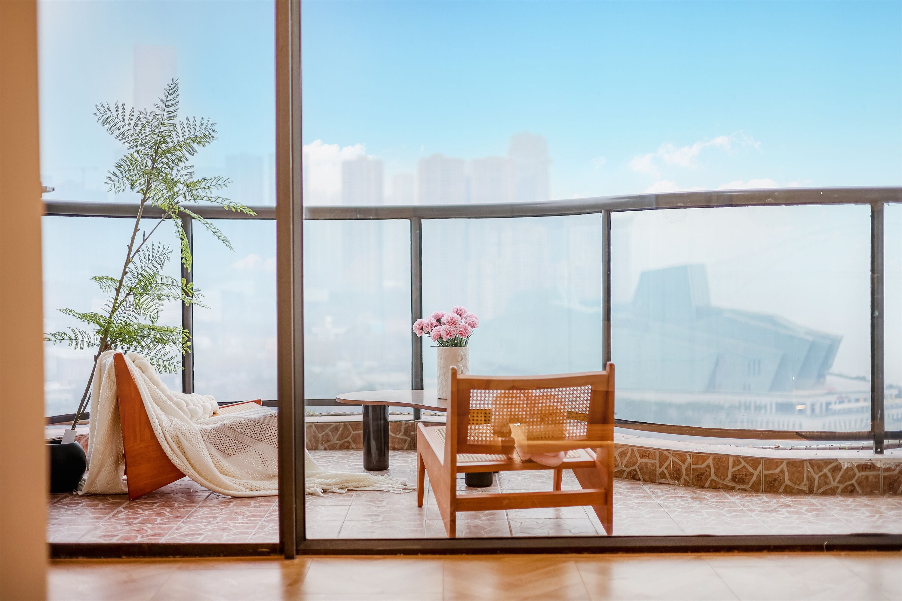 A balcony with a wooden chair, a small table, and a potted plant.