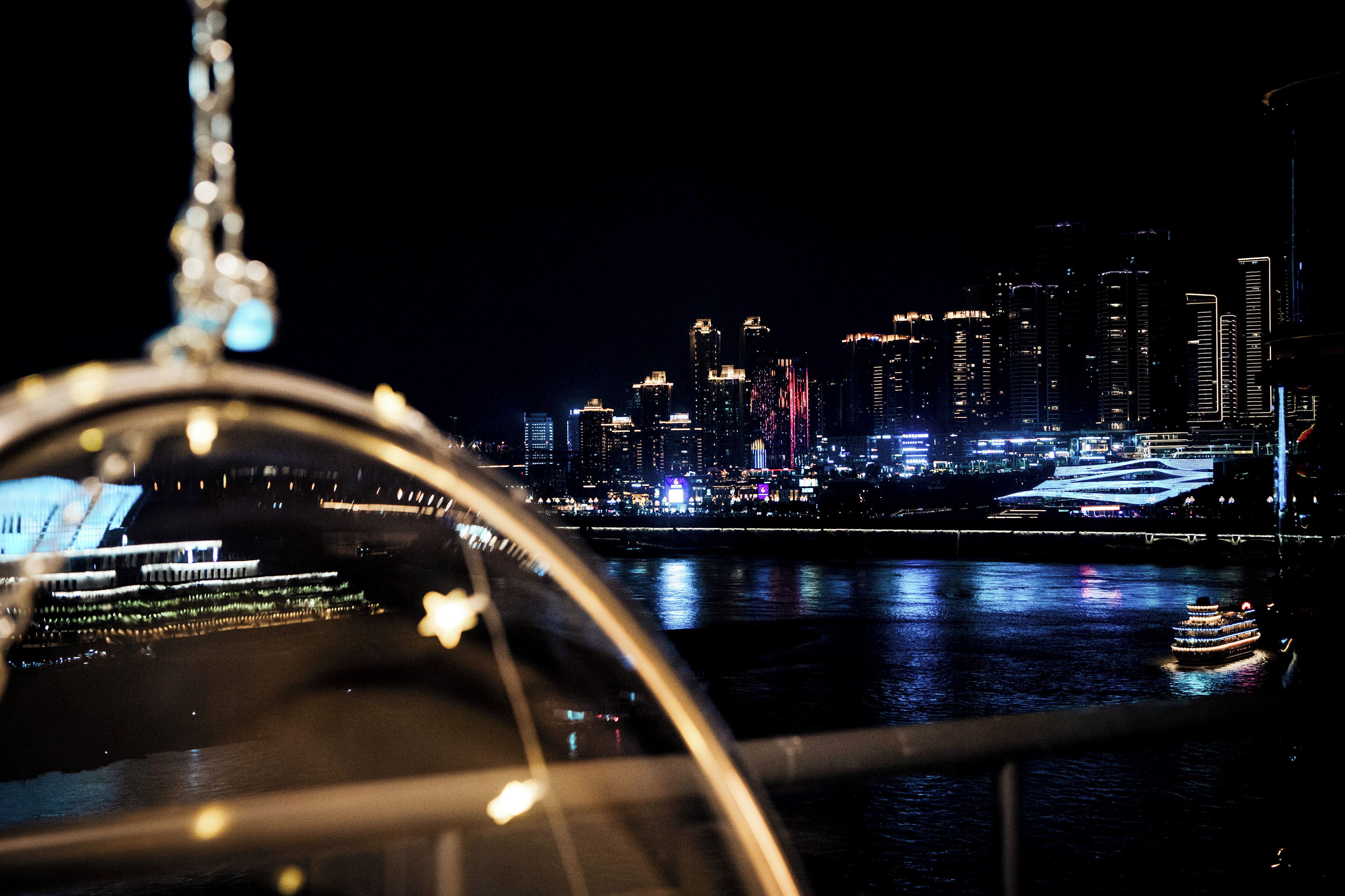 A nighttime cityscape with illuminated buildings and a river.