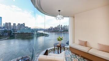 A modern room with a curved ceiling, a sofa, a small table with a vase, and a view of a city skyline and river.