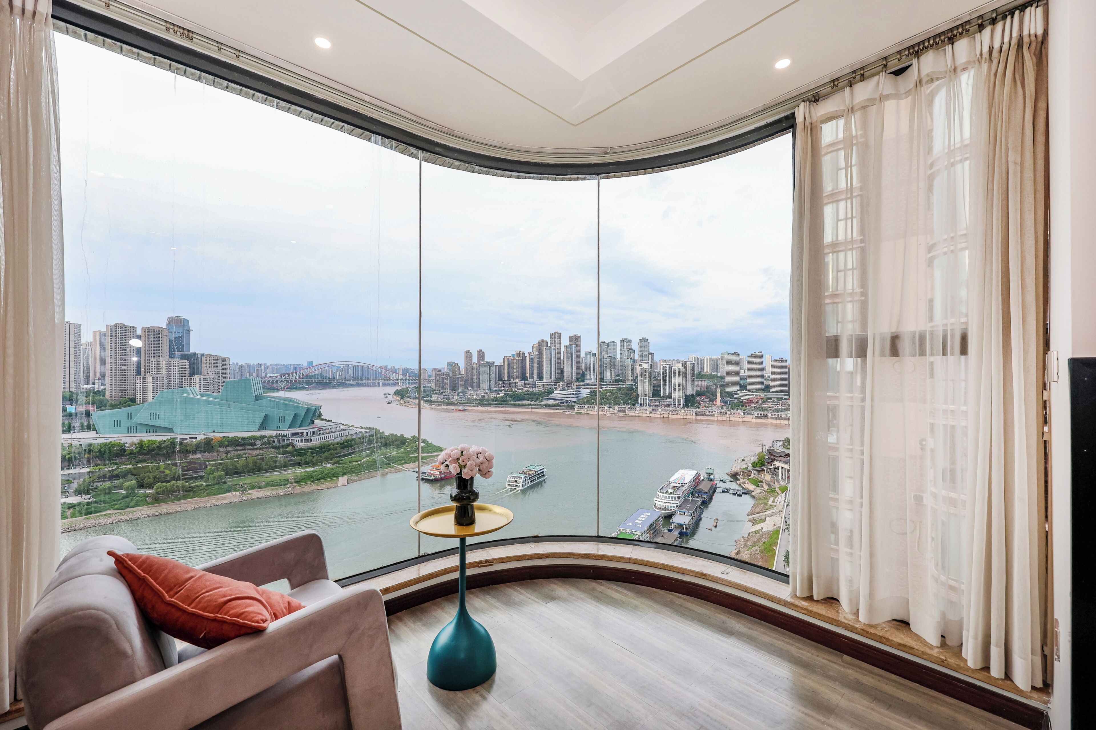 A modern room with a curved view of a cityscape and river.