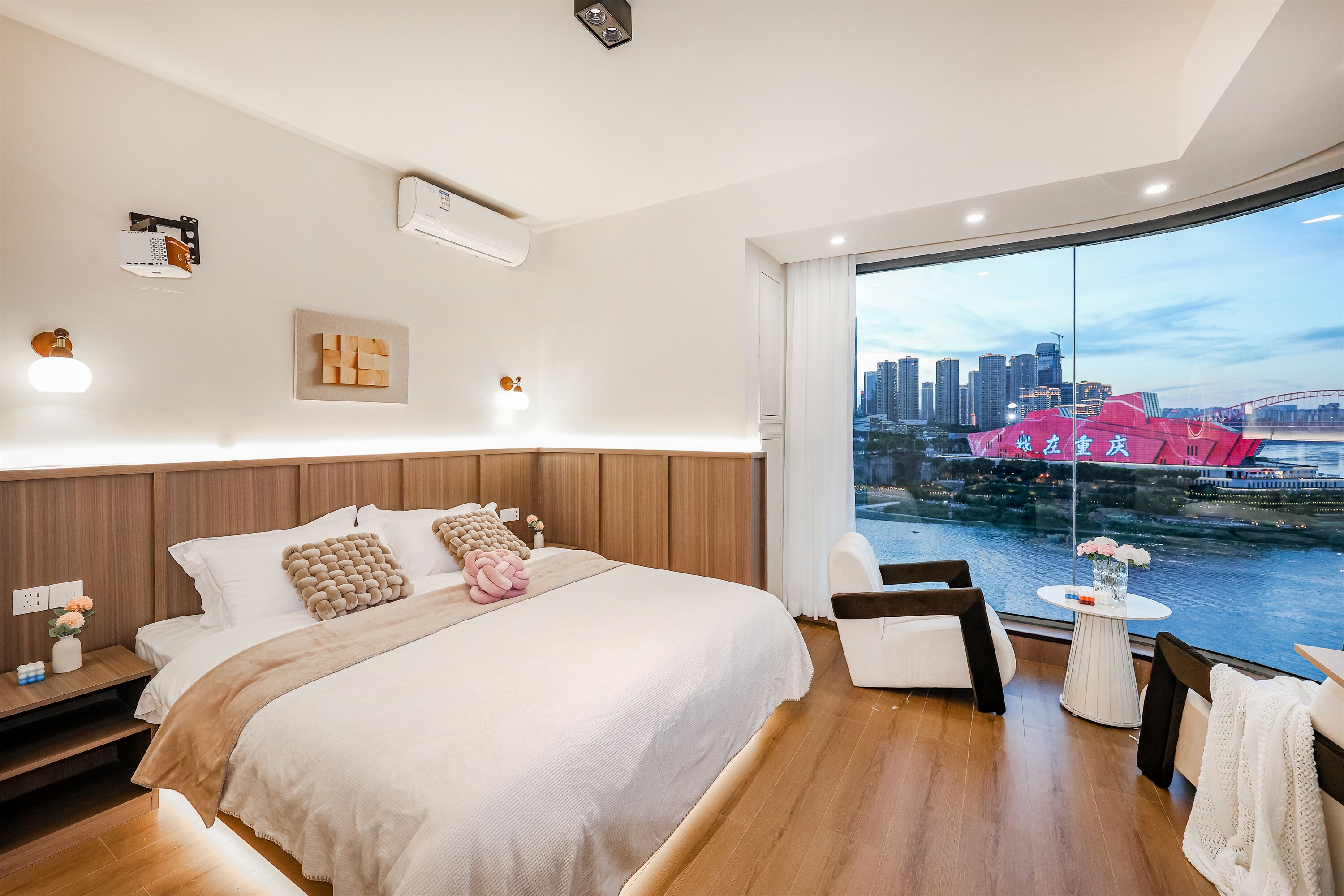 Une chambre d’hôtel moderne dotée d’un grand lit, offrant une vue sur la ville et comprenant un balcon avec une table et des chaises.