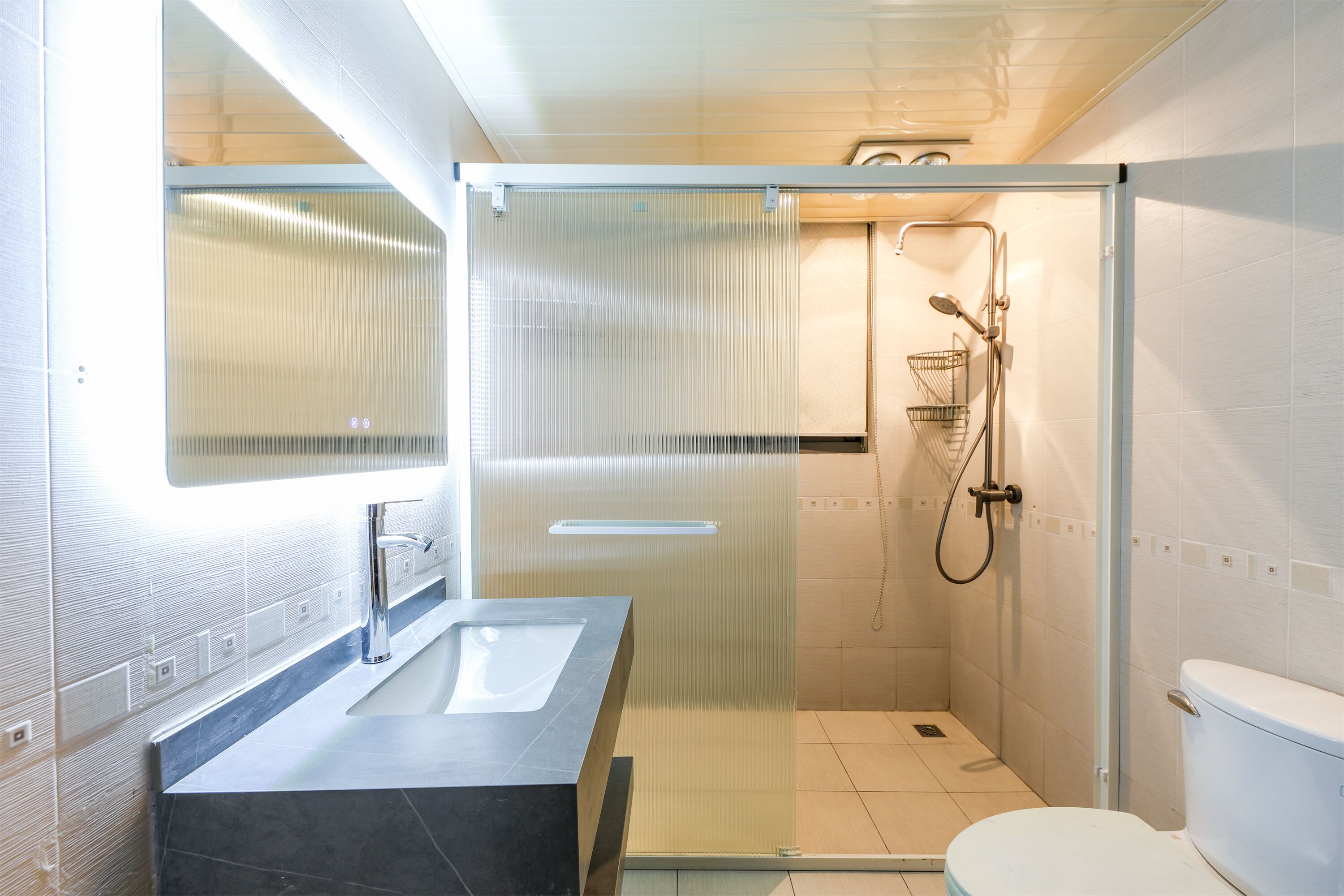 Une salle de bain moderne avec une douche à parois de verre, un lavabo avec un miroir et des toilettes.