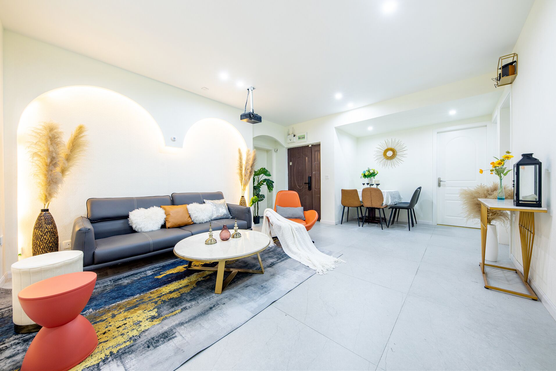 A modern living room with a sofa, coffee table, and chairs. There is a dining area with a table and chairs.