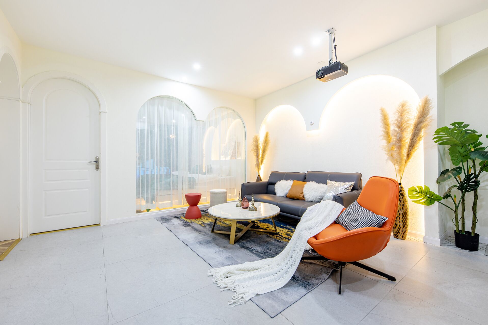 A modern living room with a sofa, armchair, coffee table, and decorative plants.