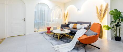 A modern living room with a sofa, armchair, coffee table, and decorative plants.