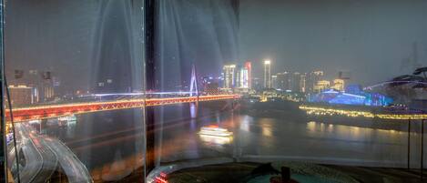 A nighttime cityscape with a prominent bridge and illuminated buildings.