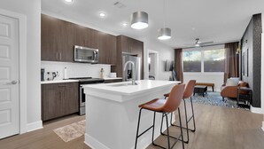 A modern kitchen with a central island, stainless steel appliances, and pendant lighting. - Southern Luxury in North ATL - 2BR 2BTH - FREE Parking (Atlanta)