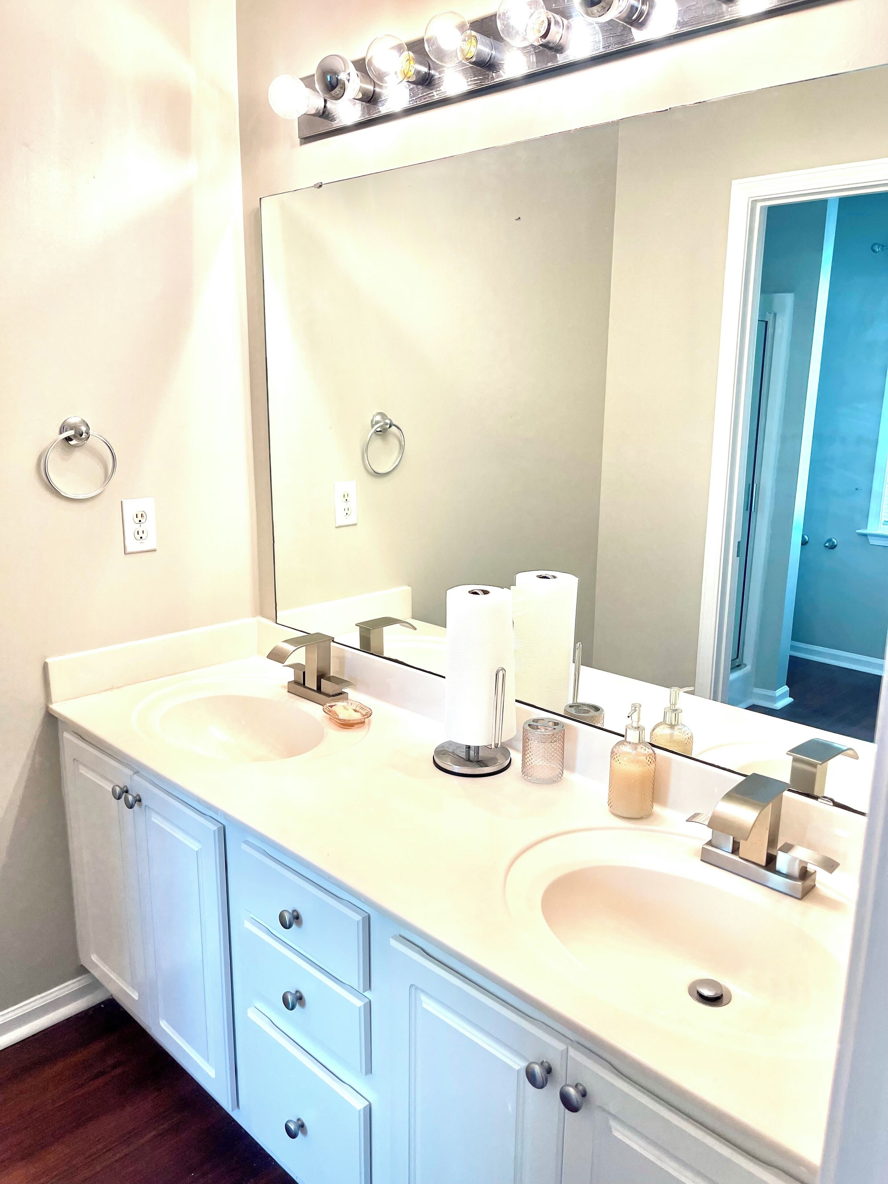Une salle de bain avec deux lavabos, un grand miroir et un meuble-lavabo avec des tiroirs.