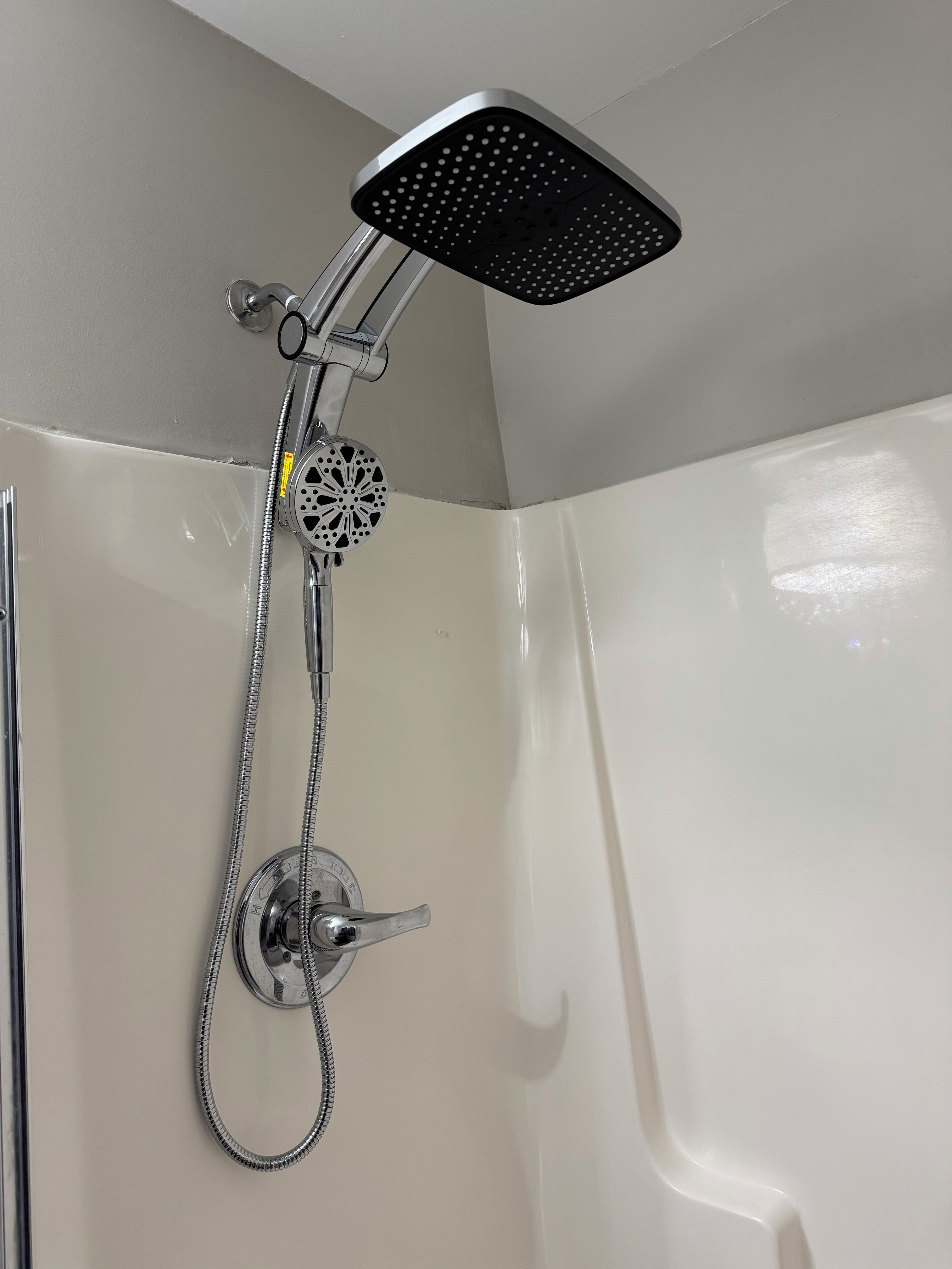 A shower with a handheld showerhead and a fixed overhead rain showerhead.