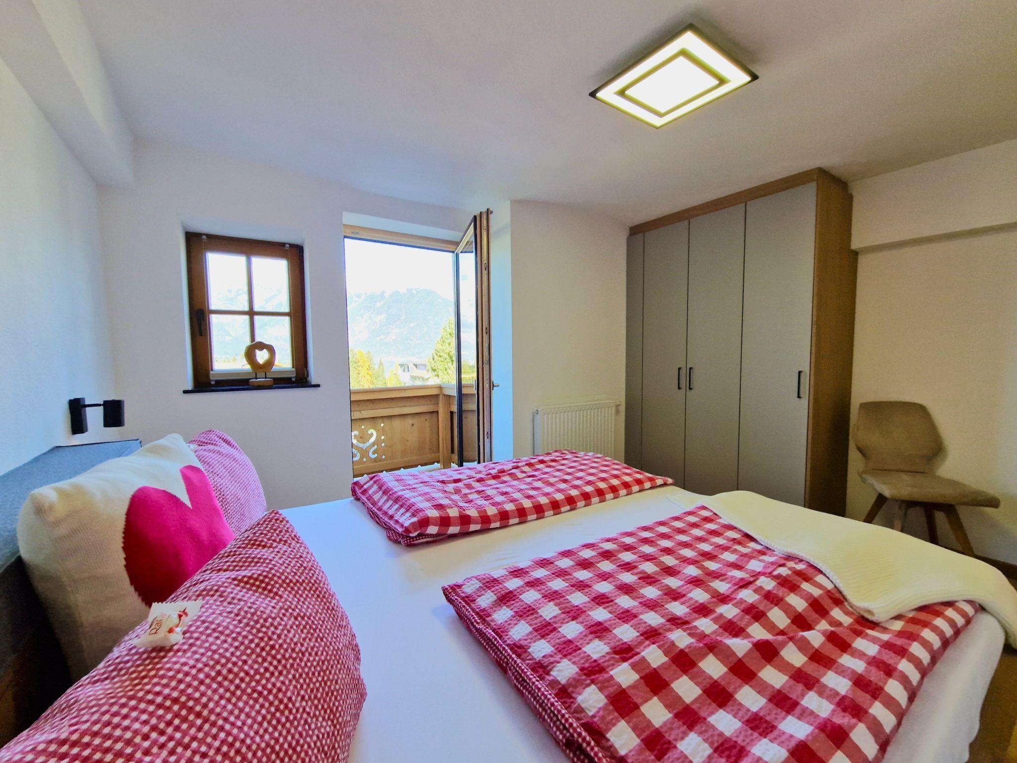 Une chambre avec deux lits, une fenêtre, une armoire et une chaise.