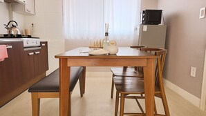 Una cocina compacta con una mesa y un banco de madera, una estufa y un refrigerador.