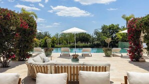 Zona piscina con poltrone, un divano e una piscina.