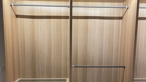 Ein begehbarer Kleiderschrank mit Holzvertäfelung, einer Metallstange und mehreren Schubladen.