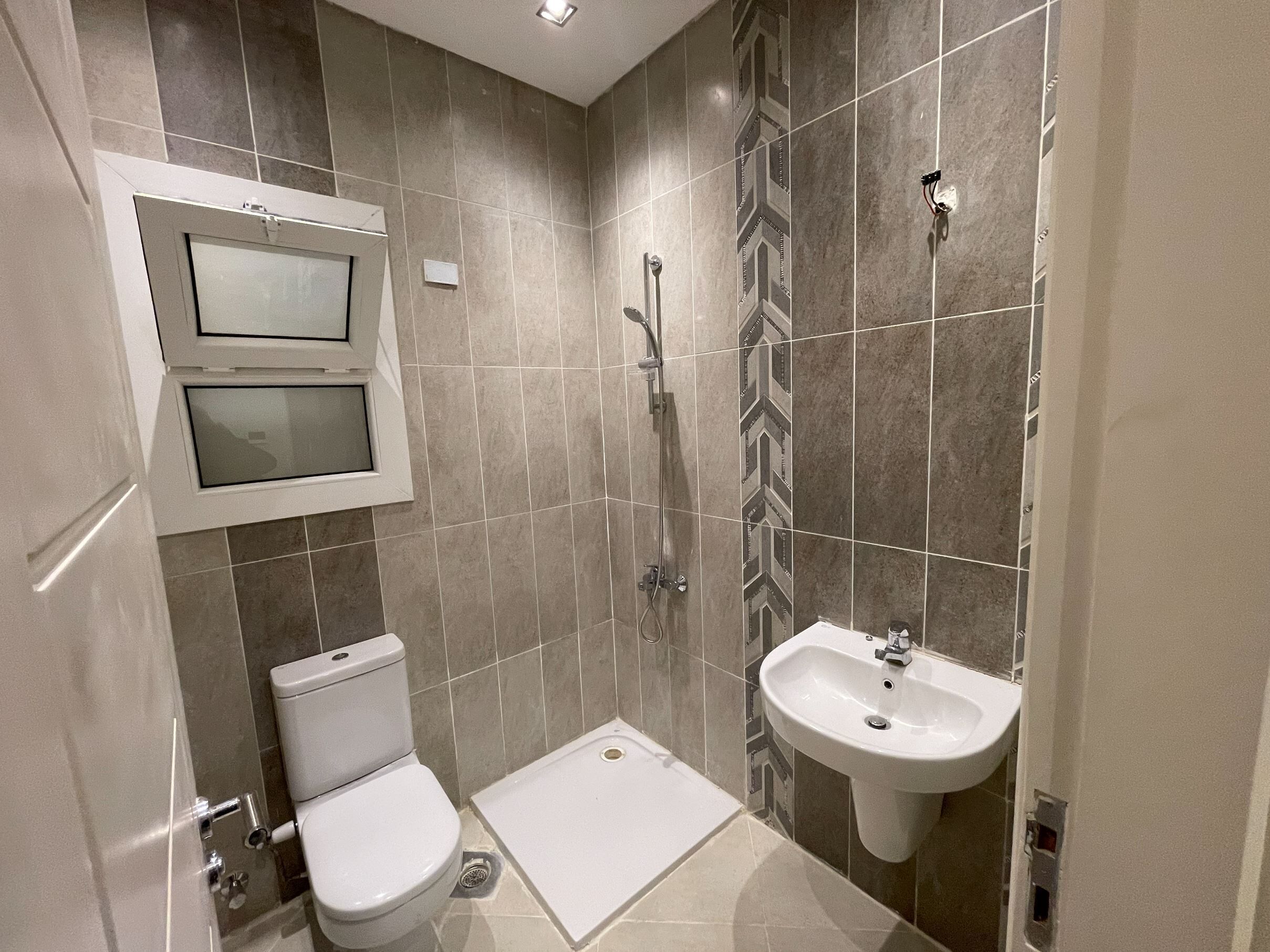 A small bathroom with a toilet, a shower, and a sink.