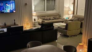 A modern living room with a sofa, a dining table, and a TV.