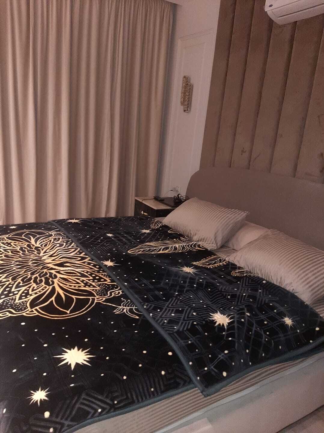 A bedroom with a bed, a nightstand, and a wall-mounted air conditioner.