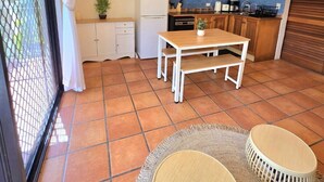 Une cuisine moderne avec un coin repas, un ventilateur de plafond et un téléviseur fixé au mur.