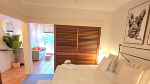 Une chambre à coucher avec un grand lit, un ventilateur de plafond, une armoire en bois et un tableau accroché au mur.