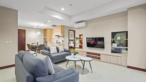 A modern living room with a grey sofa, a coffee table, and a TV mounted on the wall. - Suvin by Kozystay - Pondok Indah (Jakarta)
