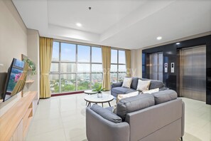 A modern living room with a sofa, a coffee table, and a TV on a wooden stand. - Suvin by Kozystay - Pondok Indah (Jakarta)