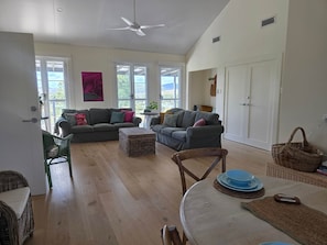 A spacious living room with two sofas, a dining table, wicker furniture, and large windows. - Unwind at new and beautiful Blue Wren Hill (Gloucester)