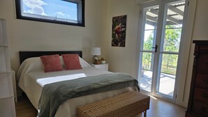 Une chambre à coucher avec un lit, une table de chevet, une lampe, une fenêtre et une vue sur l’extérieur.