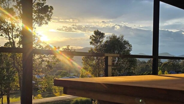 Une table de pique-nique en bois offrant une vue sur un paysage rural et des collines lointaines.