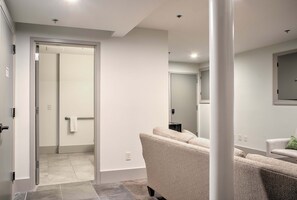 Un intérieur moderne avec un canapé, une porte donnant sur une salle de bain et un miroir au mur.