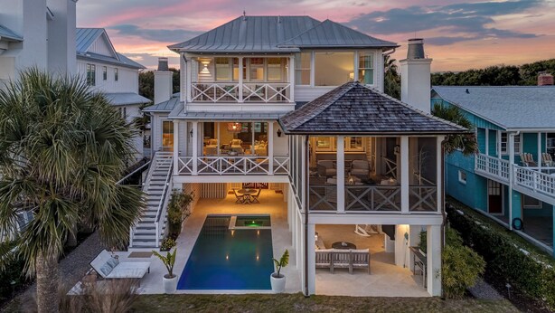 Une maison à deux étages avec un balcon, une piscine et une vue sur le coucher de soleil.